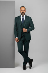 Man in tailored green three-piece suit with notch lapel, exuding modern elegance.